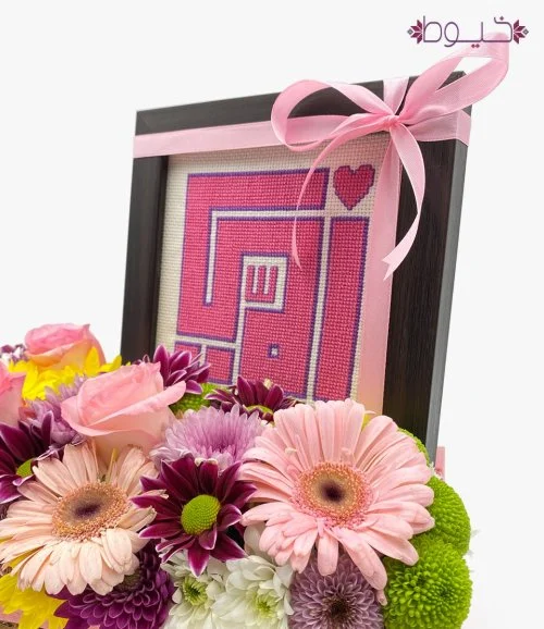 تنسيق زهور مع  إطار بتطريز كلمة "أمي" باللون الوردي 